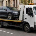Biała laweta przewożąca czarnego SUV-a na miejskiej ulicy